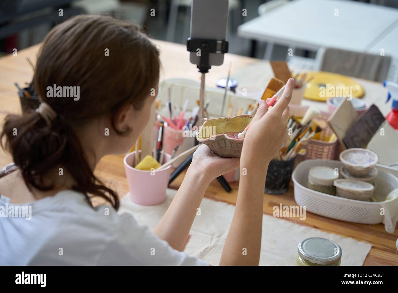 Donna tiene piatto nelle sue mani, lo decora e prende selfie Foto Stock