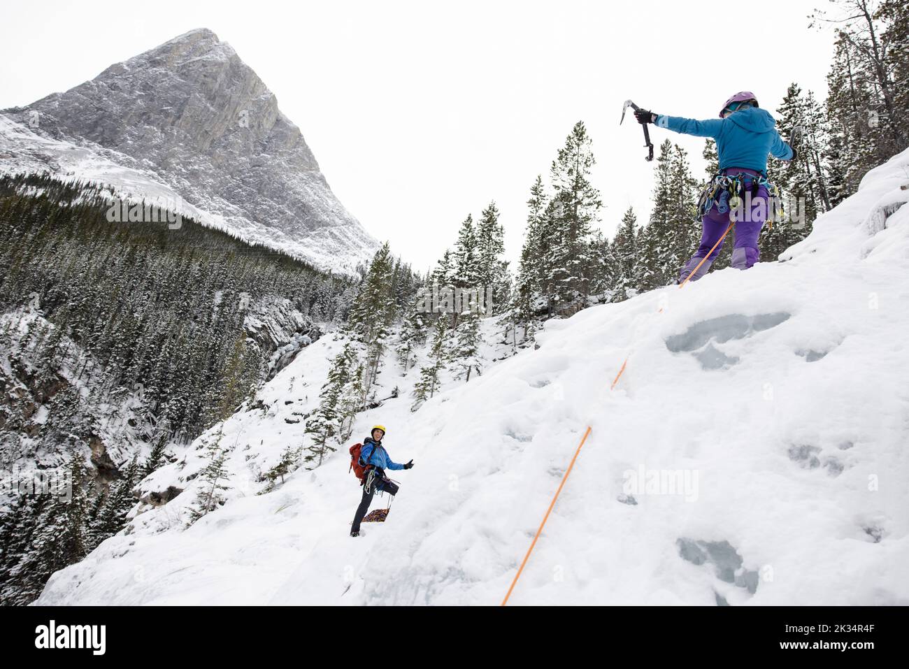 Arrampicatore di ghiaccio che si rallegra sulla cima della montagna Foto Stock