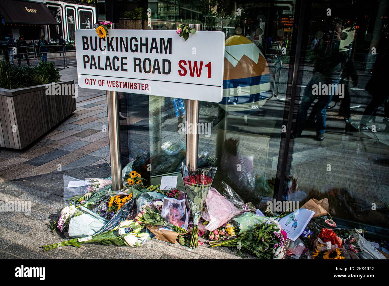 Tributi floreali alla Regina circondano un cartello stradale in Buckingham Palace Road Foto Stock