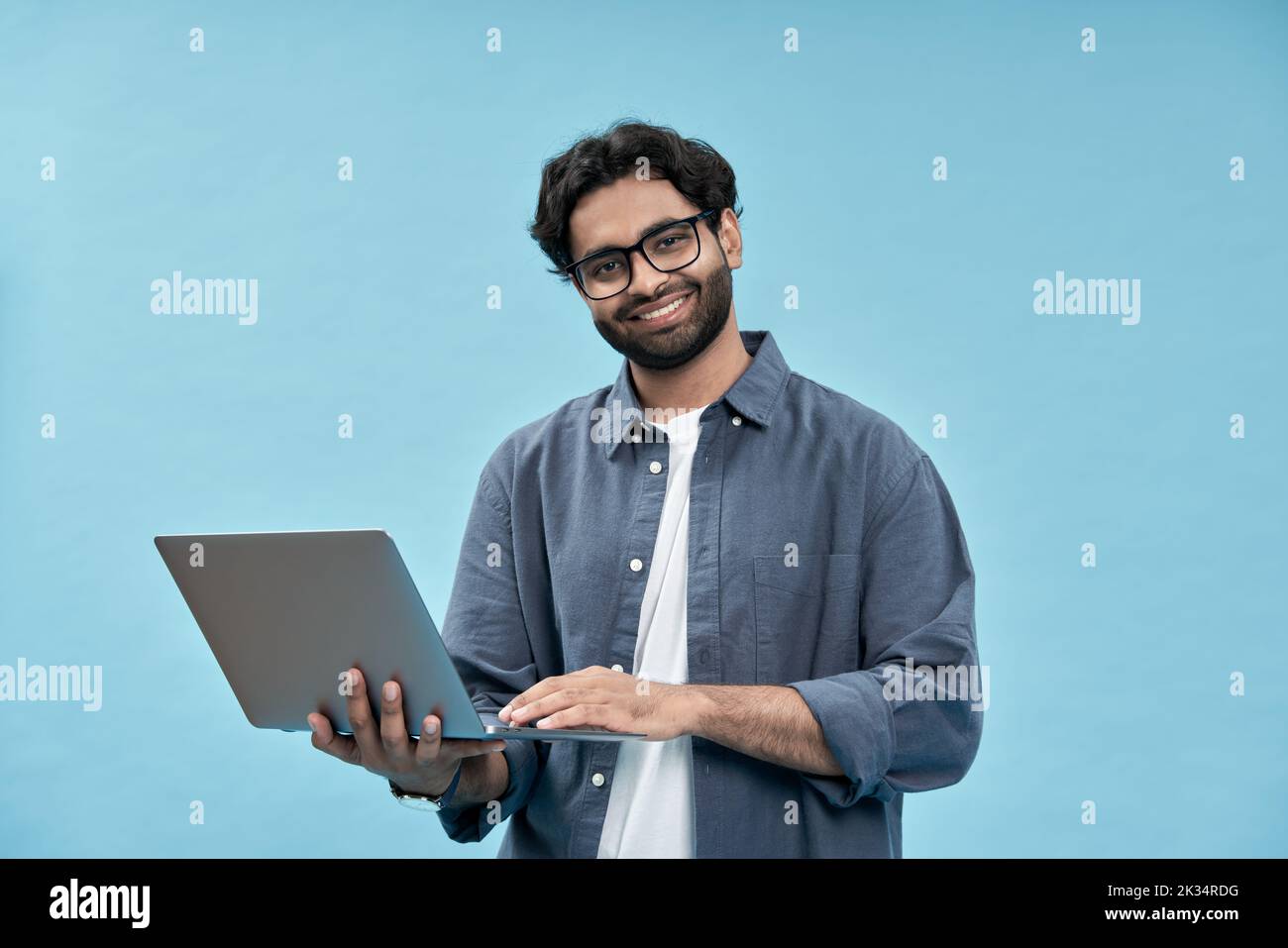 Felice uomo arabo studente di affari tenendo il computer portatile isolato su blu. Foto Stock