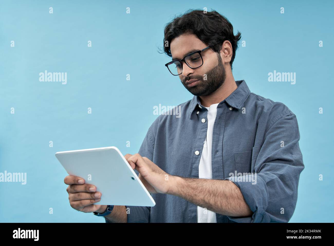Giovane arabo che usa un tablet digitale isolato su sfondo blu. Foto Stock