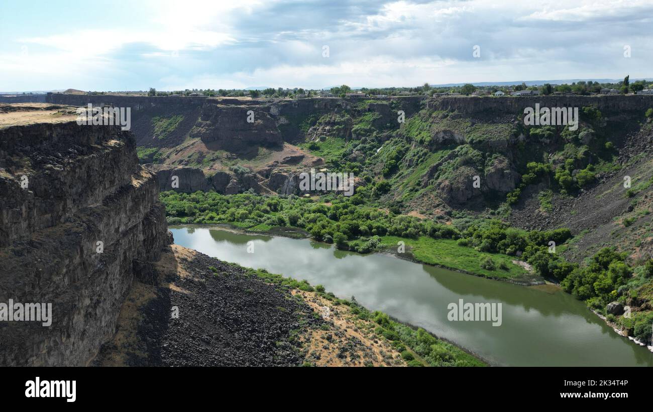 Un bel paesaggio di un fiume che scorre tra scogliere boscose sotto un cielo nuvoloso Foto Stock
