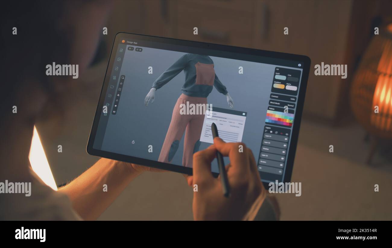 Designer 3D maschile che crea design di abiti in un'applicazione di modellazione 3D utilizzando computer tablet e matita digitale mentre lavora in remoto su un progetto freelance Foto Stock