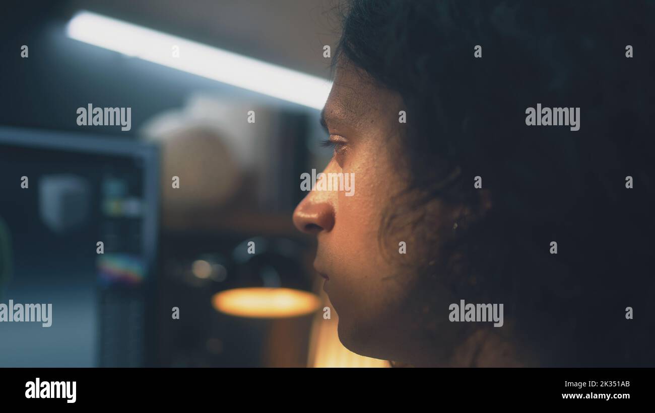 Primo piano di un uomo concentrato che guarda lo schermo del computer mentre lavora in remoto su un progetto di modellazione 3D freelance da casa Foto Stock