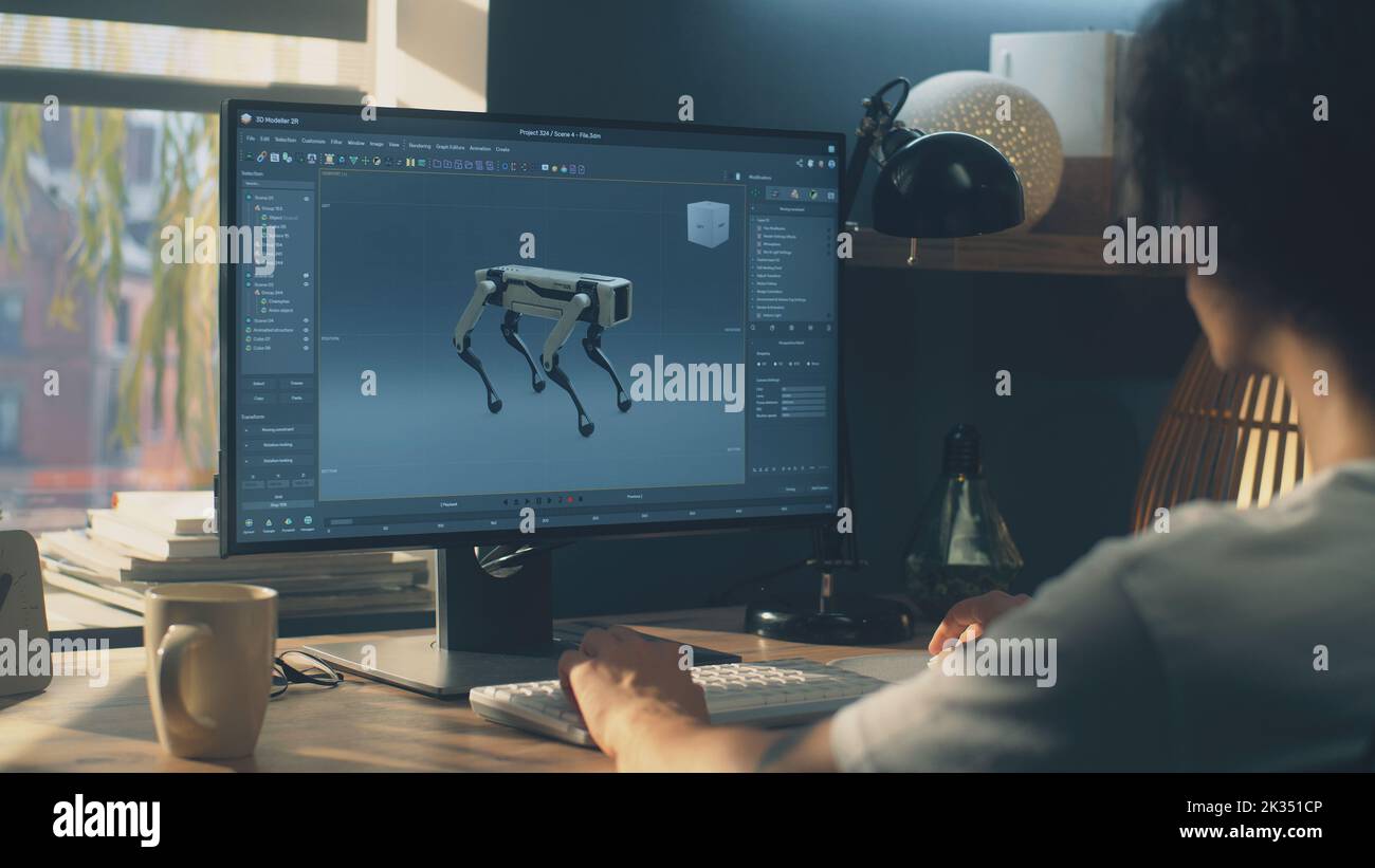 Uomo seduto al tavolo e che crea un prototipo 3D di robot moderno mentre lavora su pc in un programma di modellazione 3D in remoto dall'ufficio domestico Foto Stock