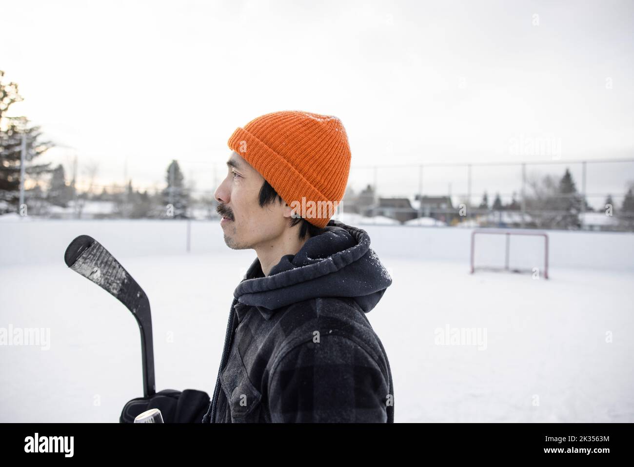 Profilo ritratto uomo che prende una pausa da hockey su ghiaccio sulla pista di pattinaggio invernale Foto Stock