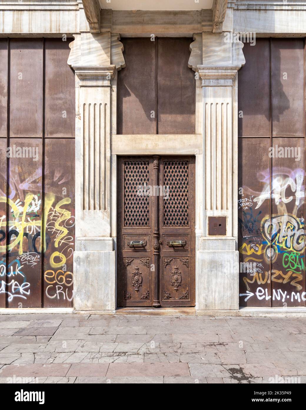 Esterno di una porta in metallo arrugginito che mediava due colonne in marmo in un edificio abbandonato sulla strada cittadina Foto Stock