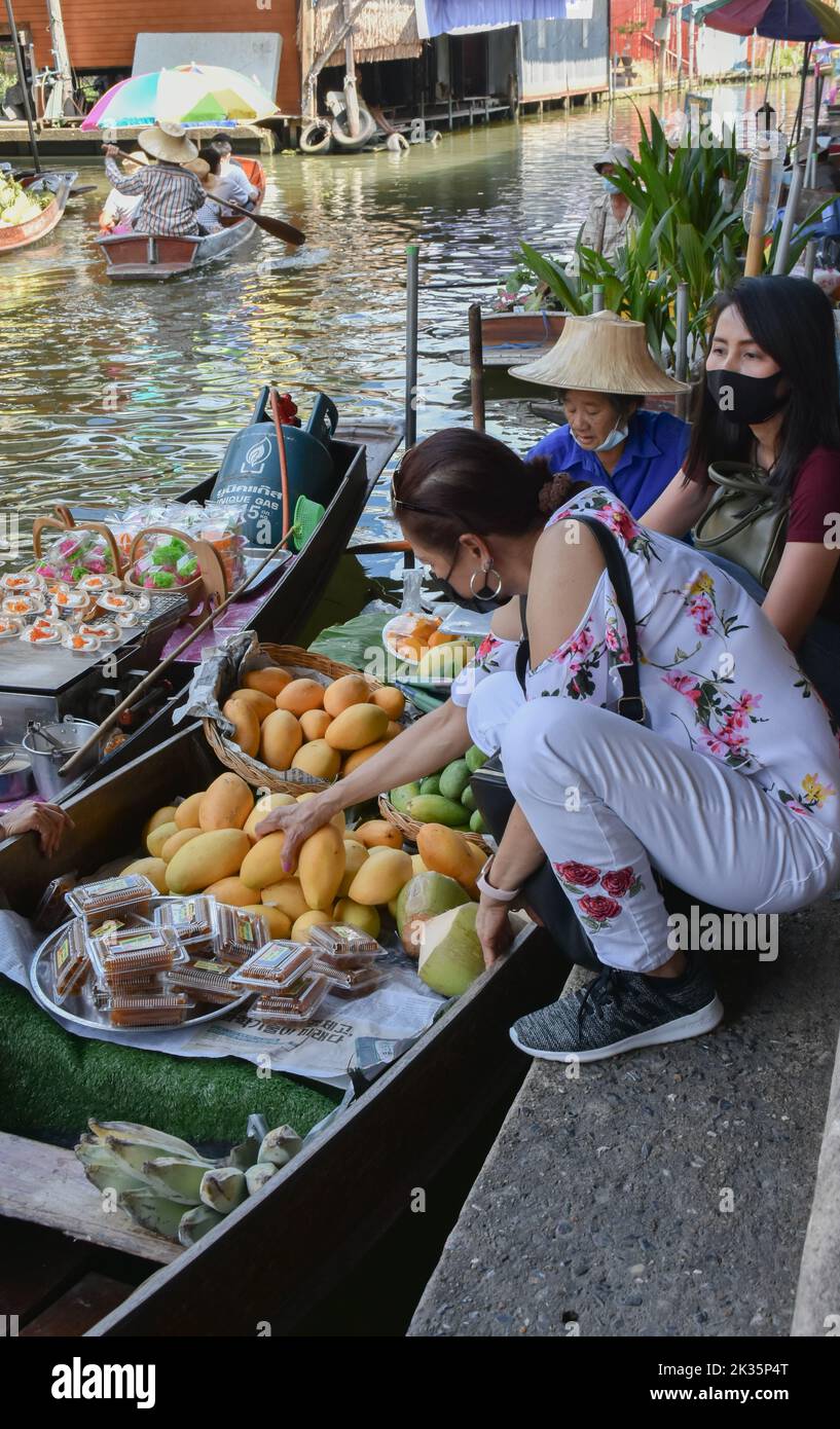 Ratchaburi, Thailandia 10 aprile 2022 - Damnoen Saduak mercato galleggiante venditori in Thailandia che vendono frutta, verdura e prodotti dalla loro barca. Foto Stock
