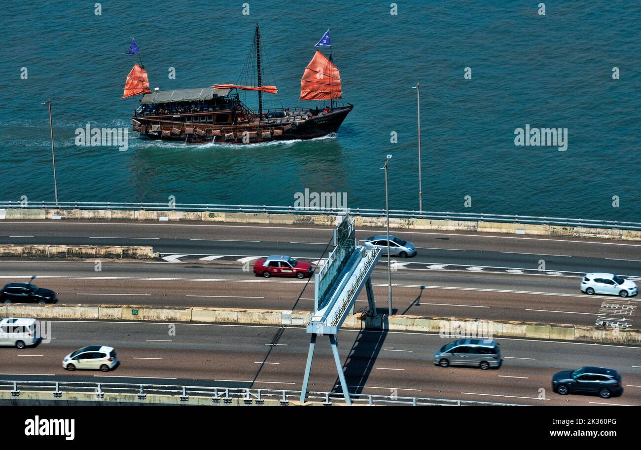 Autostrada sopraelevata e la famosa giunca turistica a vela rossa, Hong Kong, Cina. Foto Stock
