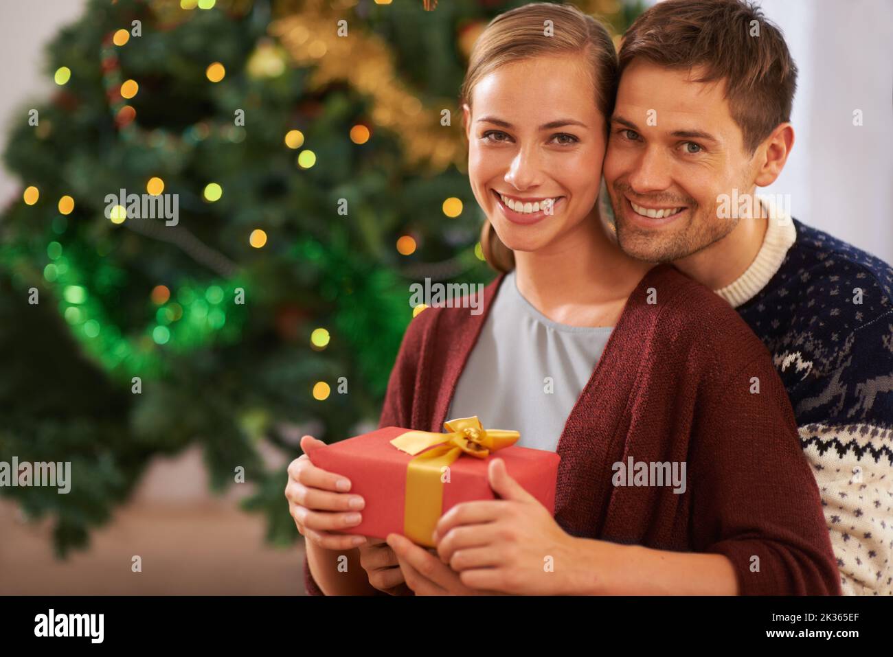 Il Natale è il momento di dare, una giovane coppia affettuosa il giorno di Natale. Foto Stock