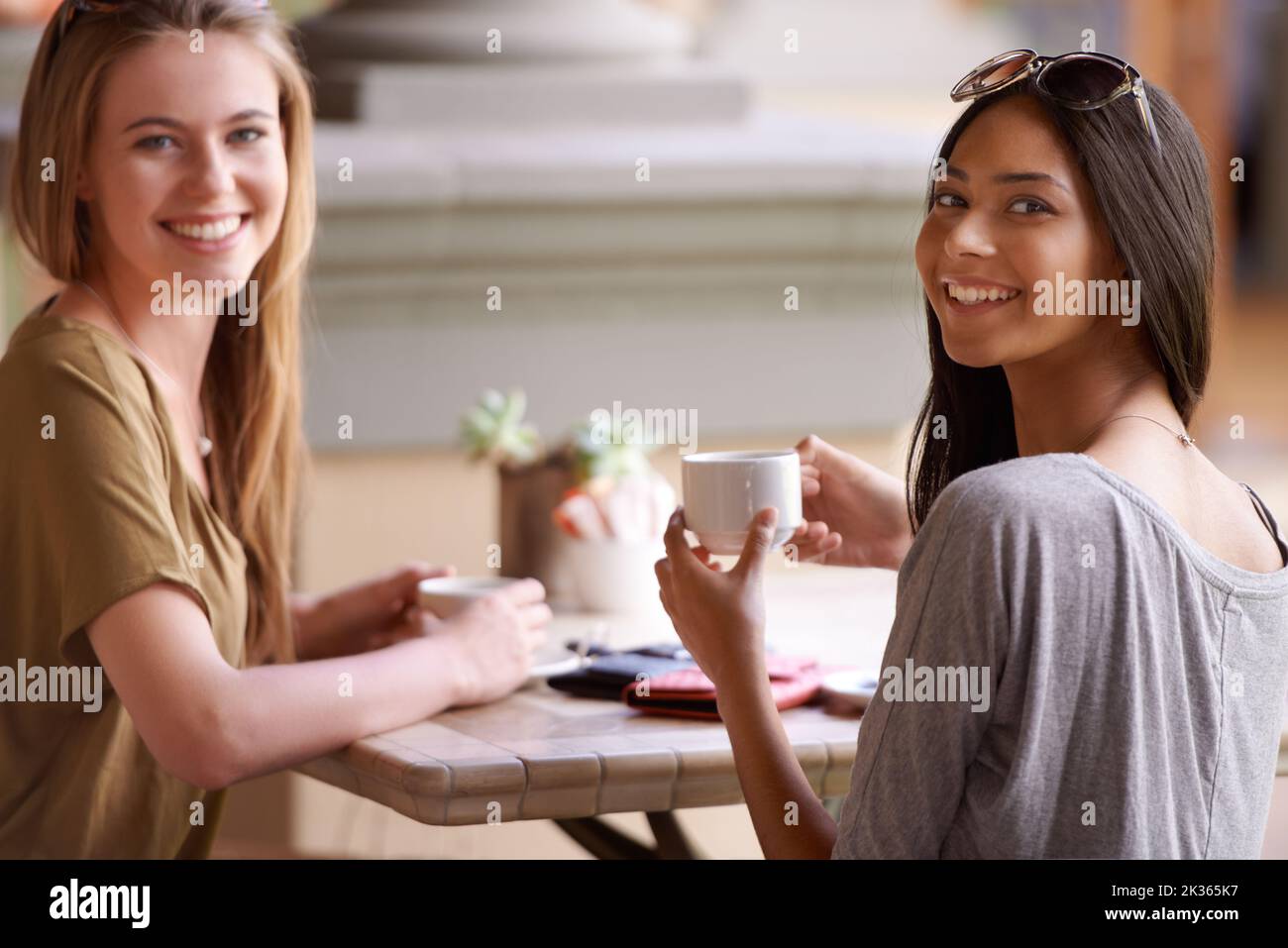 Un po' di caffè con il mio pestio. Due giovani donne attraenti che gustano un caffè in un bistrot. Foto Stock