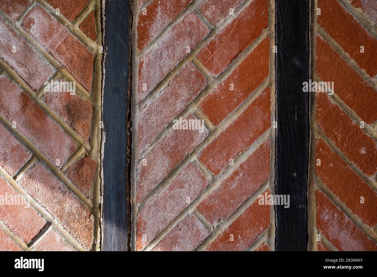 Picchiettio di mattoni rossi a spina di pesce tra legname verticale nero Foto Stock