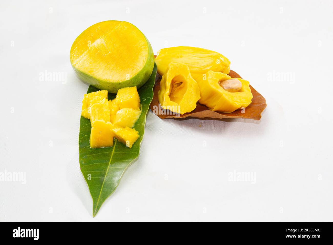 Jackfruit e mango tagliati sulle foglie. Frutta tropicale estiva in Asia. Foto isolata in studio. Rinfrescante insalata di frutta calda per il giorno. Foto Stock