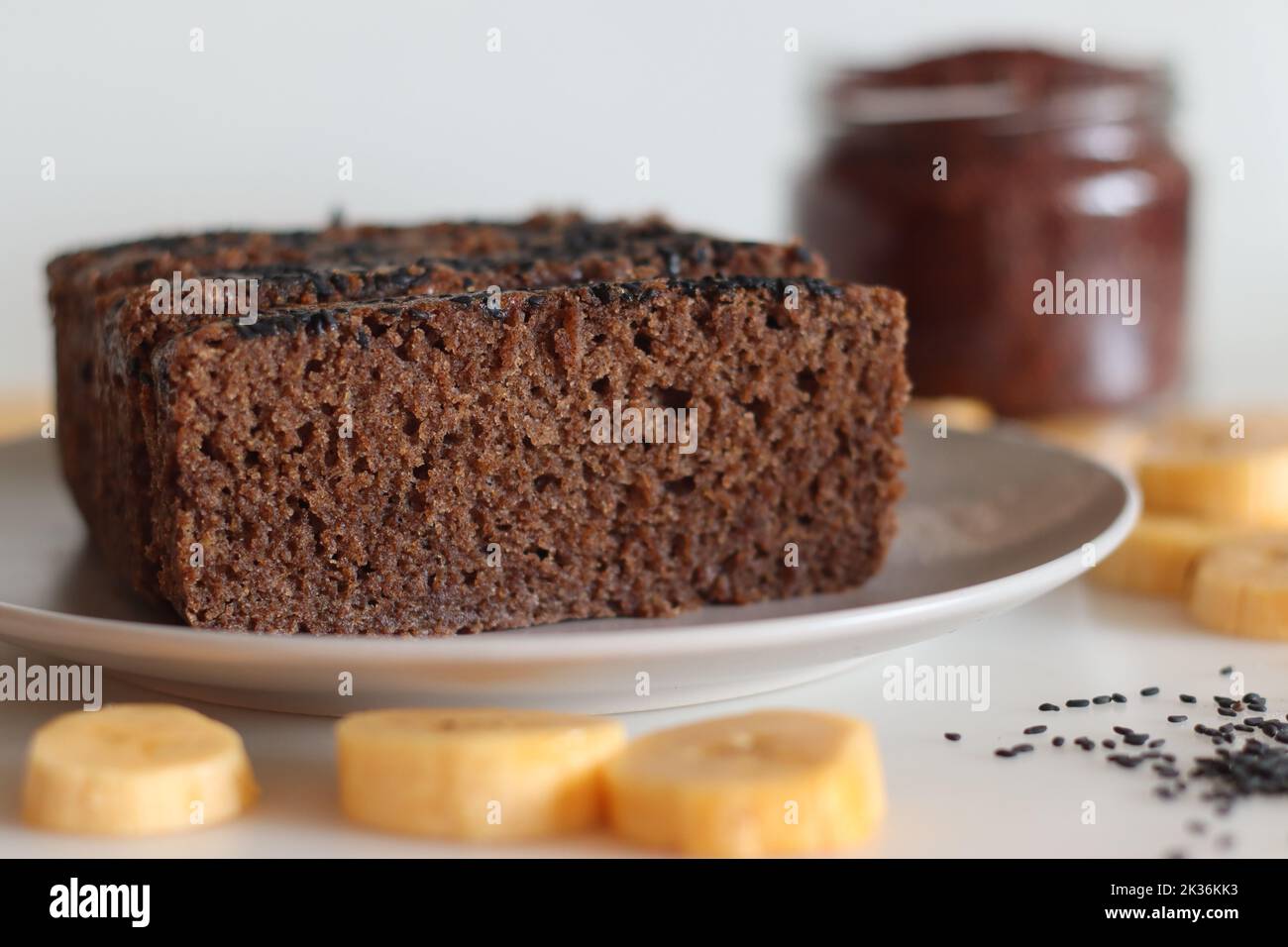 Torta ragi plantain. Torta da tè senza glutine fatta di farina di miglio Finger e piantina matura purea, cosparso di semi di sesamo nero sulla parte superiore. Foto in bianco Foto Stock