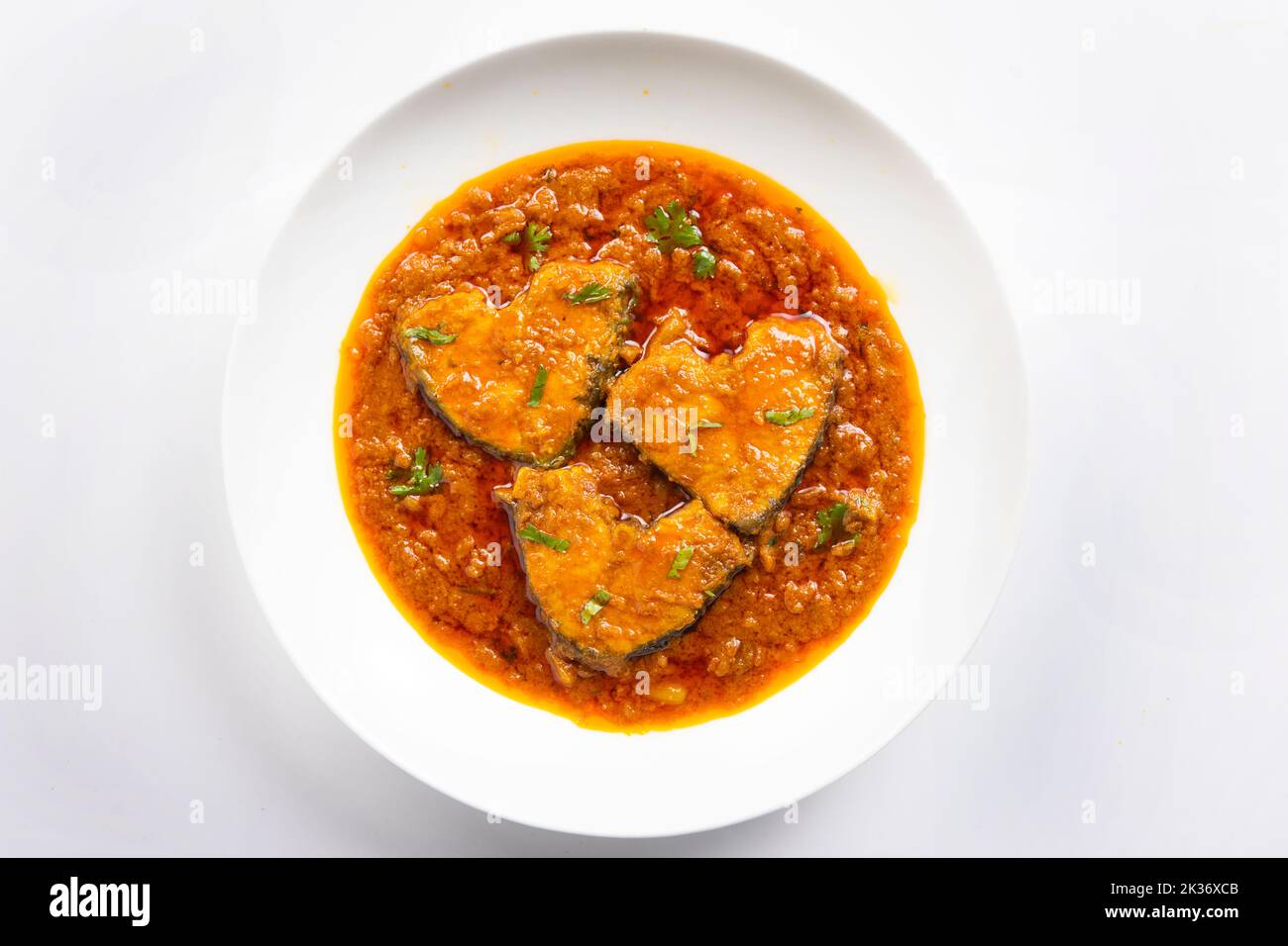 Katla Fish curry, tradizionale curry di pesce indiano, sistemato in una ciotola di ceramica bianca guarnita con fresco rosso freddo. Isolato su fondo bianco, top Foto Stock
