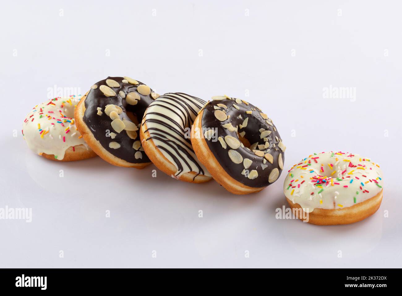 Ciambelle tradizionali americane con cioccolato e glassa rosa e spruzzate isolate su uno sfondo bianco. Close-up.Donuts. Foto Stock