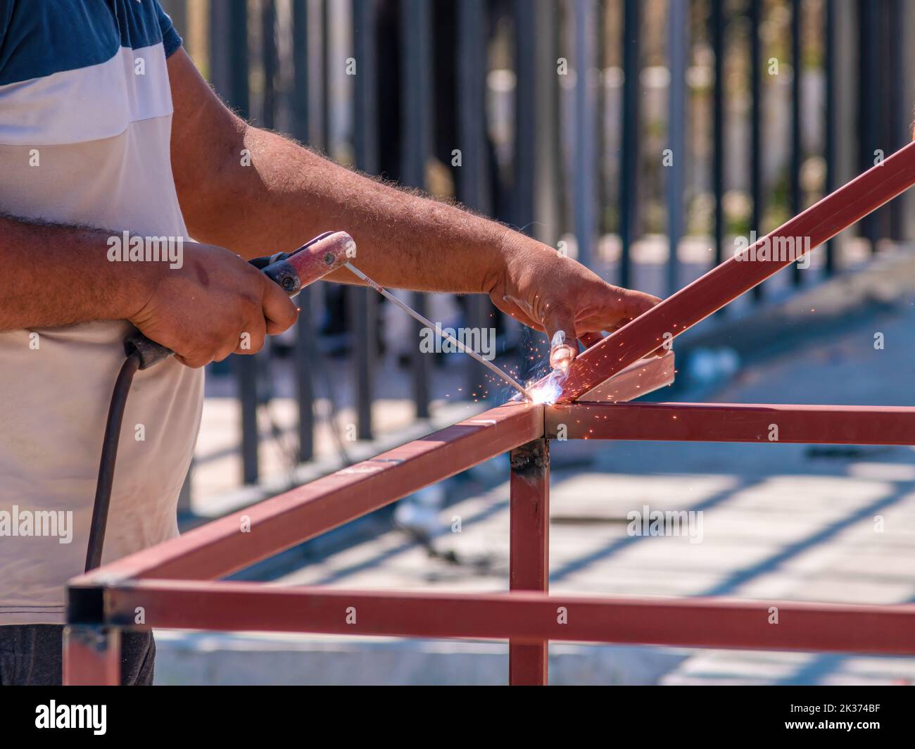 Saldatrice saldatura di due profili in ferro in cantiere in una giornata di sole Foto Stock