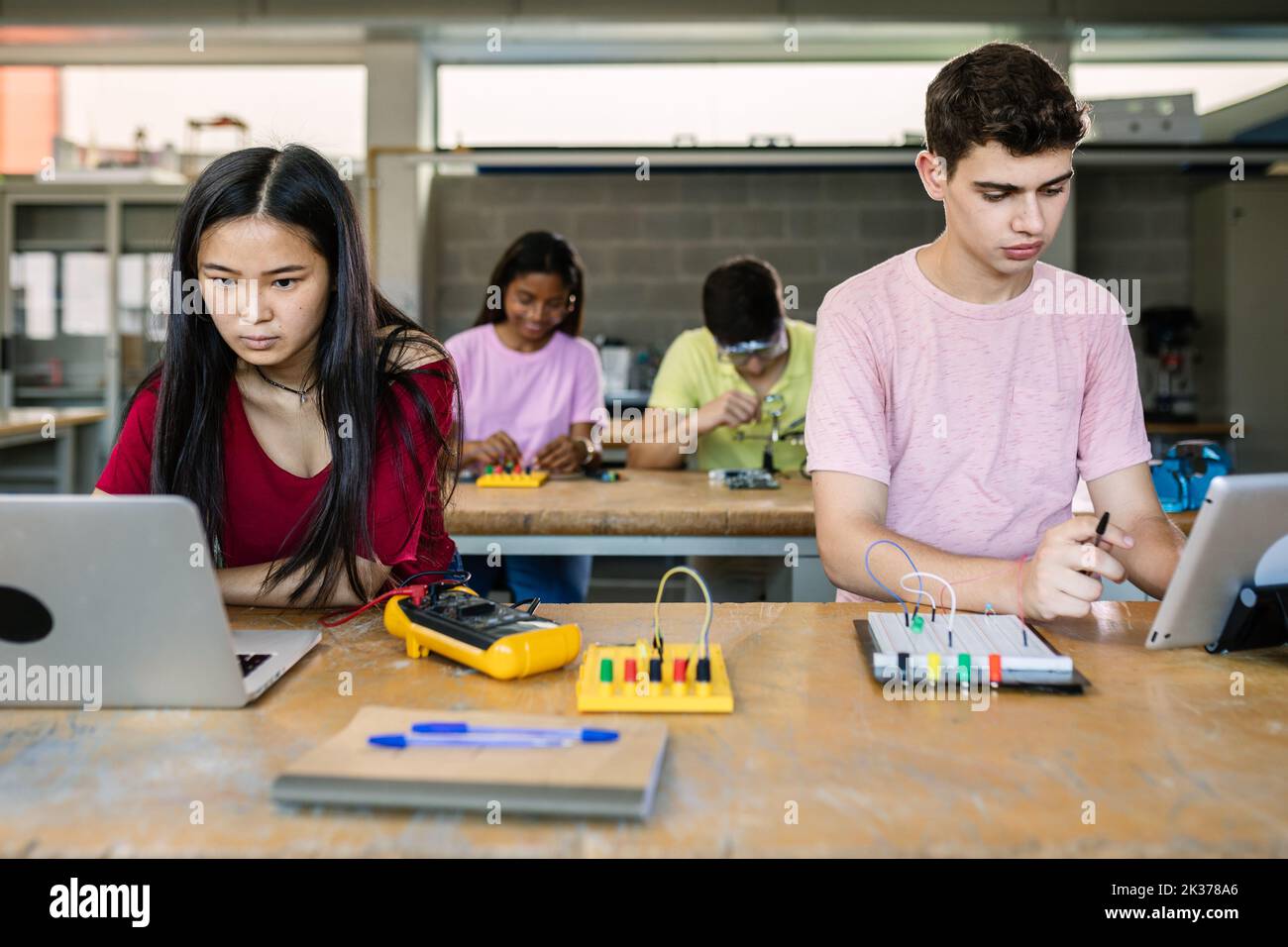 Gruppo multirazziale di studenti delle scuole superiori che programmano circuiti elettronici Foto Stock
