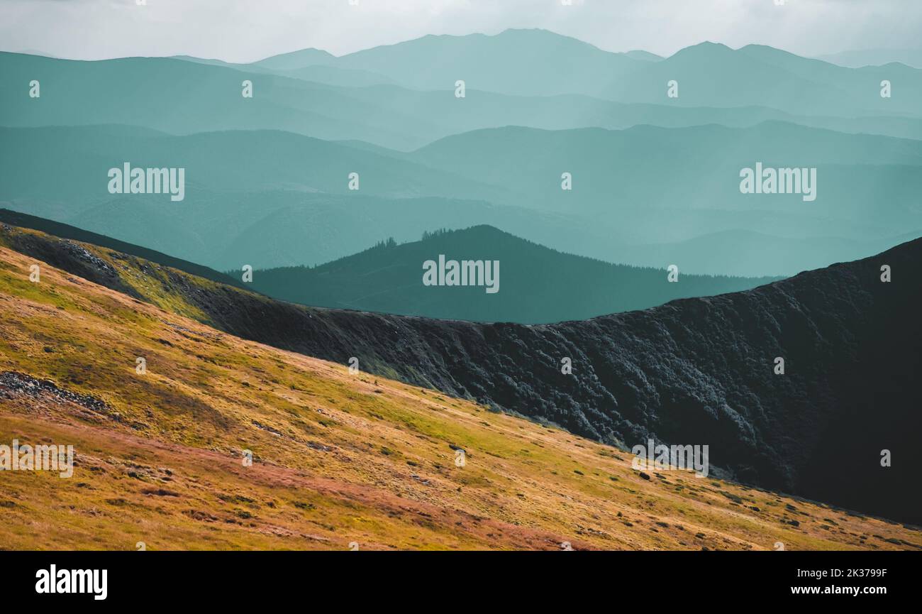 Panorama della catena montuosa in autunno mattina. Pendio di collina di erba arancione, silhouette di altopiani blu, cima della montagna. Viaggi, escursioni, libertà, stile di vita attivo. Carpazi montagne, Ucraina Foto Stock