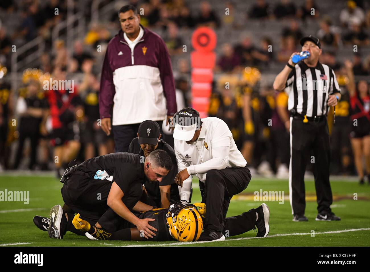 Il capo allenatore provvisorio dello stato dell'Arizona Shaun Aguano controlla il suo giocatore ferito con il personale di formazione nel primo trimestre di un footbal dell'università NCAA Foto Stock