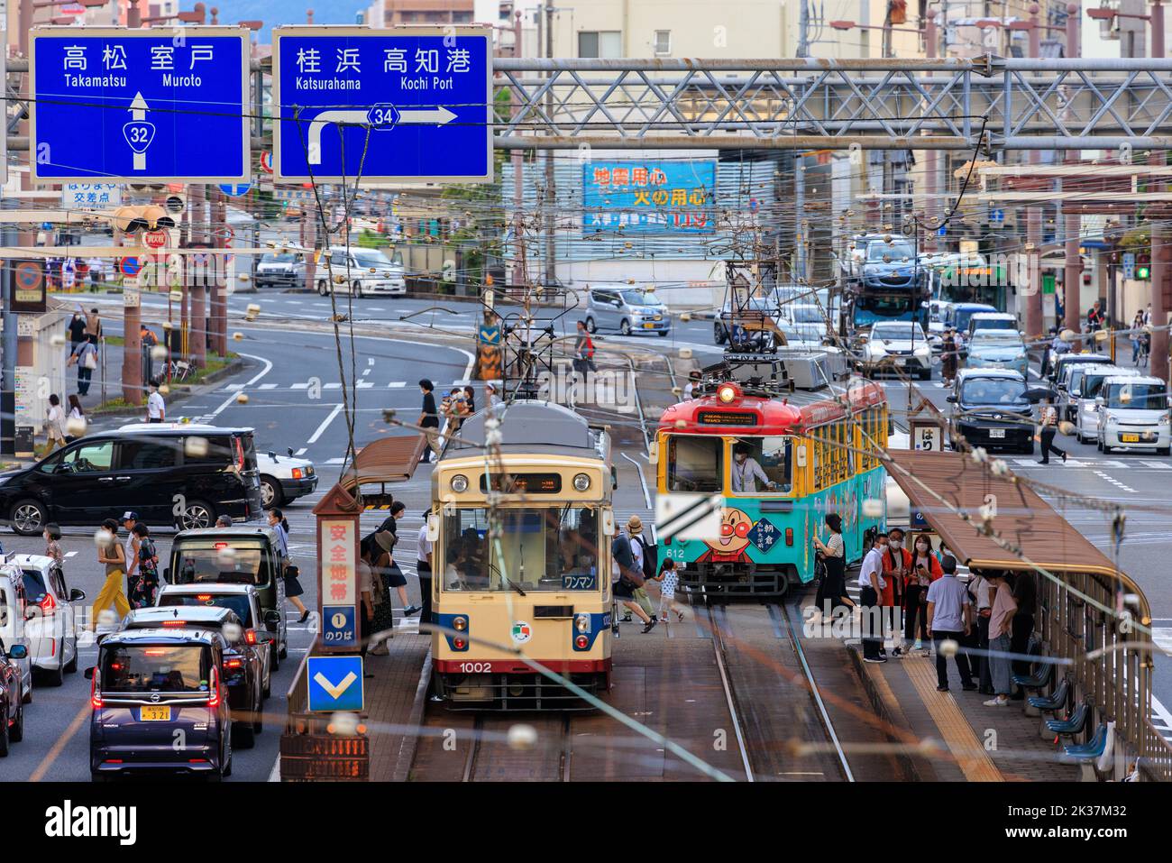 Kochi, Giappone - 10 agosto 2022: I passeggeri salpano a bordo di tram in mezzo al traffico leggero del centro città Foto Stock