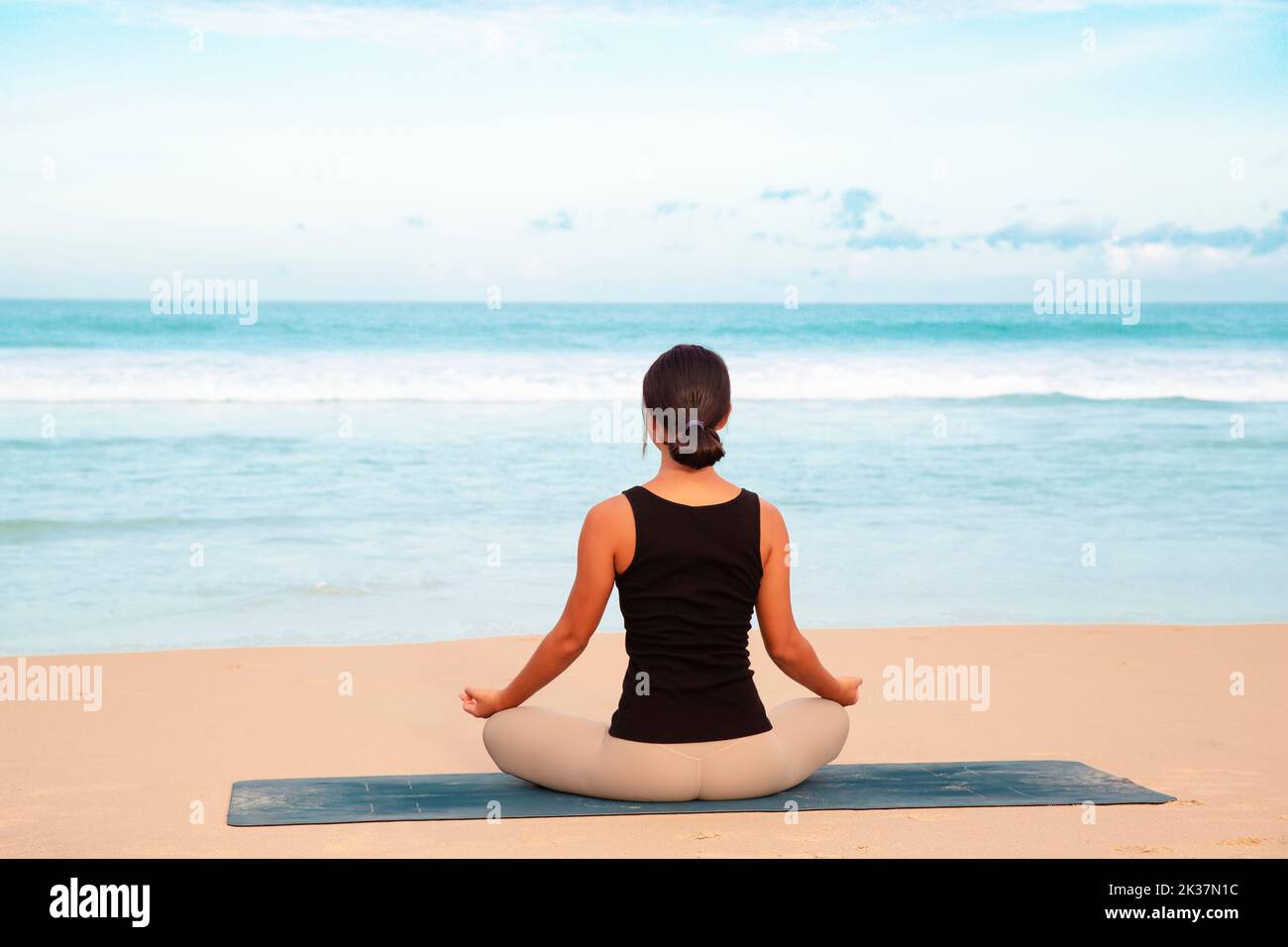 donna che pratica yoga a riva del mare di spiaggia tropicale, giovane donna meditare in spiaggia fare esercizi di yoga Foto Stock