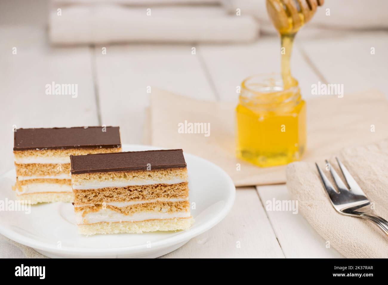 Torta al miele con condimento al cioccolato e panna bianca al burro. Dolce di nozze fatto in casa dessert. Servita su tavolo di legno bianco. Foto Stock