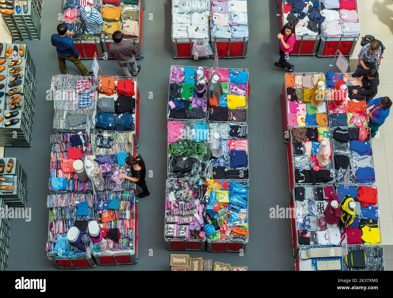 Clienti che controllano attraverso i tavoli di abbigliamento in uno dei molti centri commerciali della città. Repubblica di Singapore Foto Stock