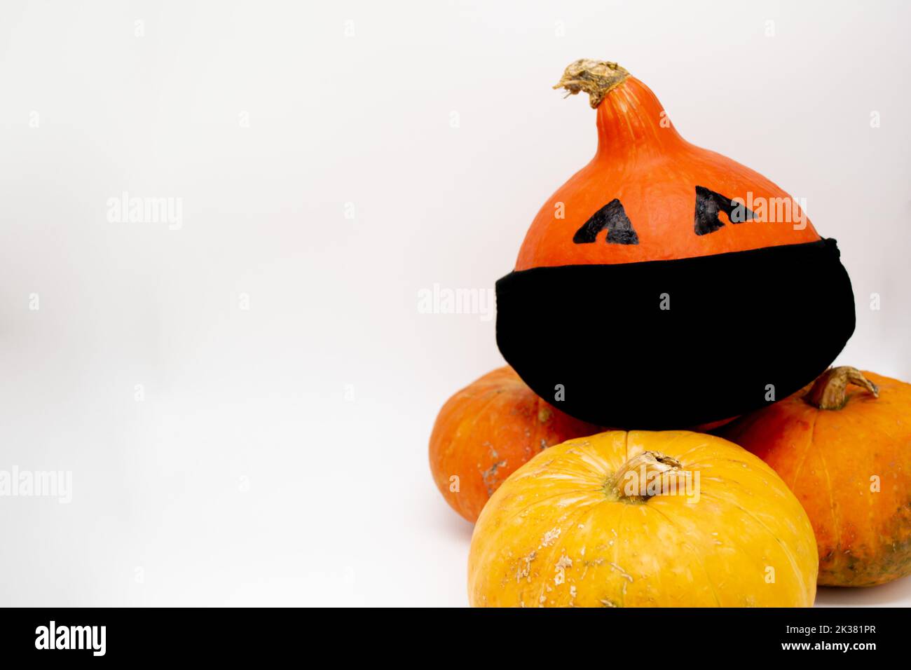 Zucche arancioni, una con gli occhi in una maschera nera, si trova sopra le altre. Spazio di copia. Foto Stock