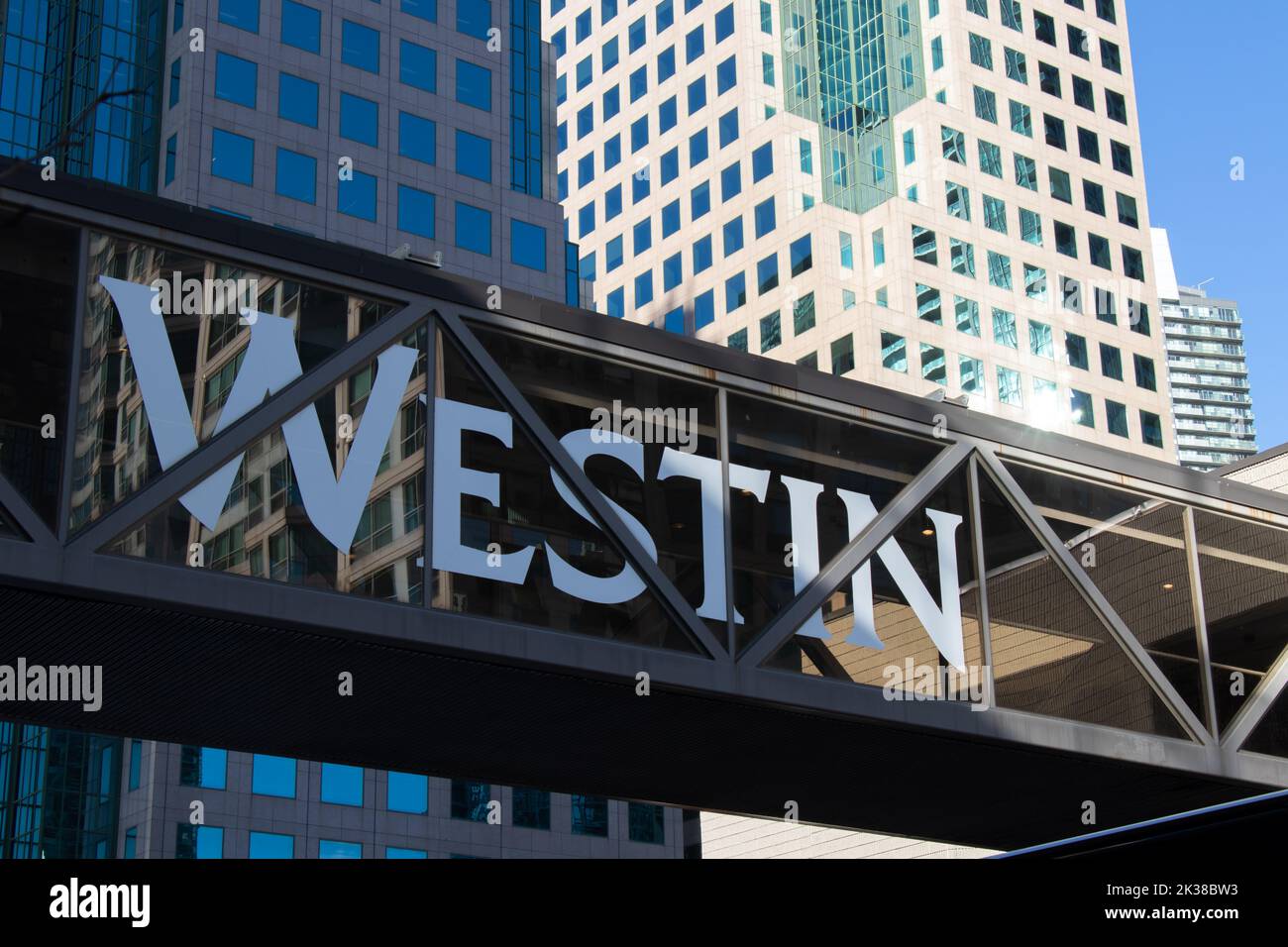Il Westin Hotels and Resorts, un logo di una catena alberghiera di lusso, è visto un ponte che attraversa il centro di Toronto mentre il sole splende sugli alti edifici. Foto Stock