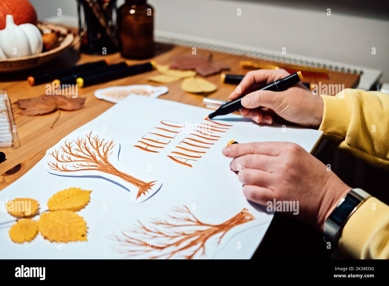 Ciao scritta autunnale. Disegno di stagione di autunno, come disegnare il disegno e la pittura di scrittura di caduta. Scritta autunnale sul tavolo con pitture, pennelli e. Foto Stock