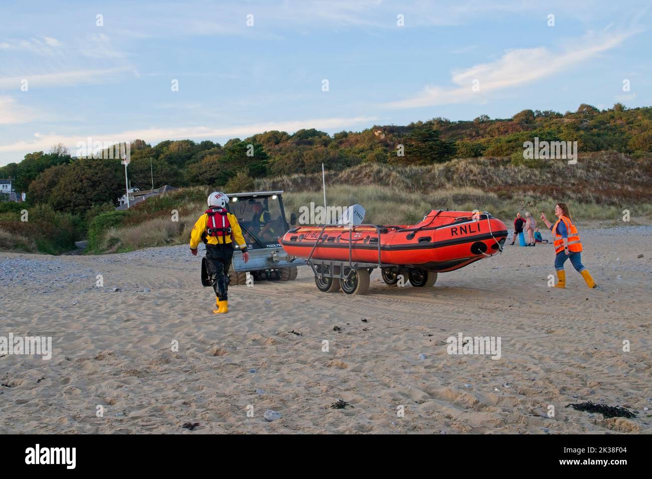 Horton Beach Gower Wales UK RNLI, imbarcazione di salvataggio costiera di ritorno alla stazione di bagnamento dopo l'esercizio con l'aiuto di un veicolo di recupero della spiaggia e dell'equipaggio sulla spiaggia Foto Stock