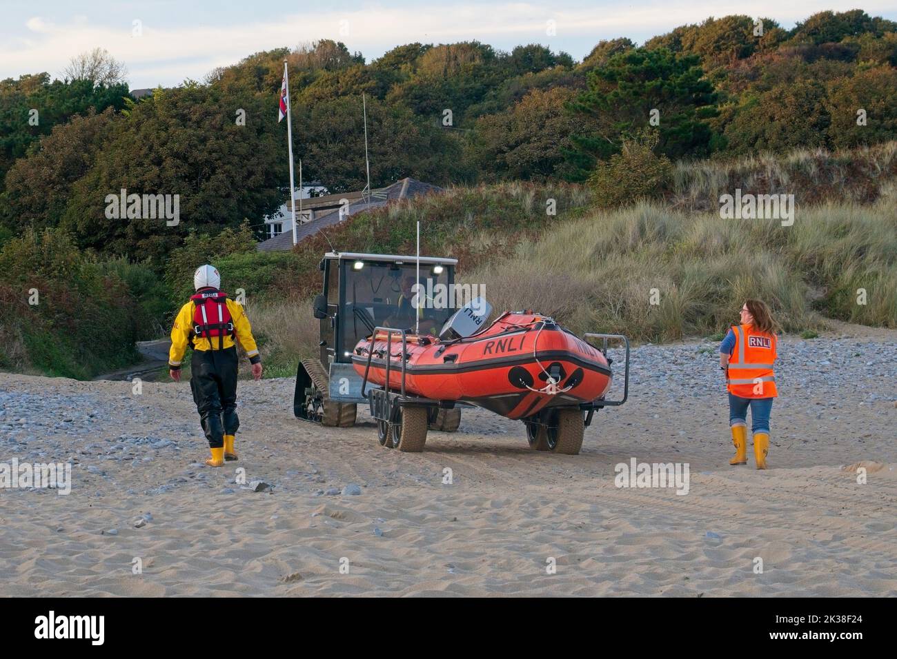 Horton Beach Gower Wales UK RNLI, imbarcazione di salvataggio costiera di ritorno alla stazione di bagnamento dopo l'esercizio con l'aiuto di un veicolo di recupero della spiaggia e dell'equipaggio sulla spiaggia Foto Stock