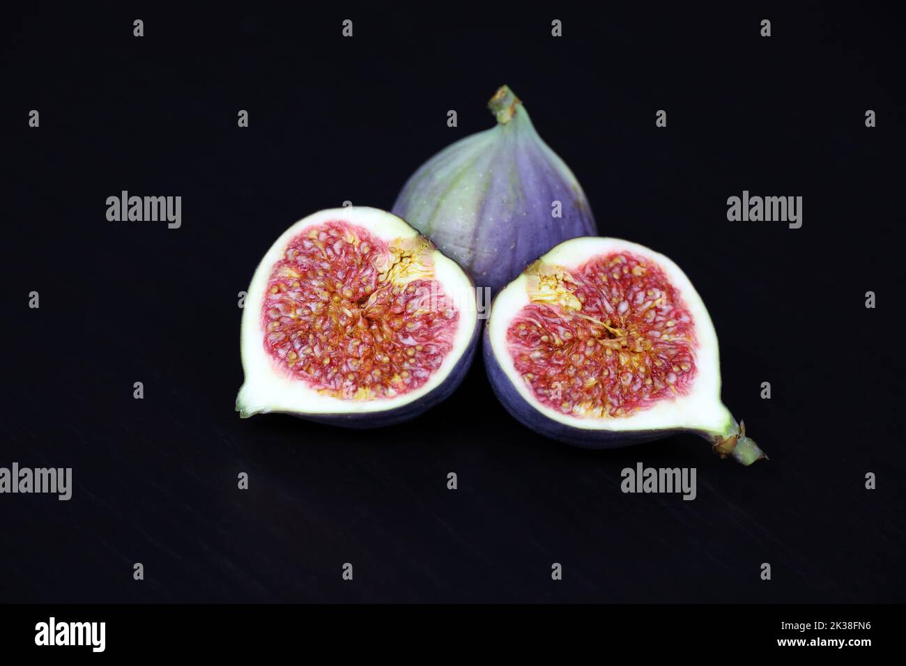 Fichi maturi, semi tagliati e frutti interi su tavola di legno scuro Foto Stock