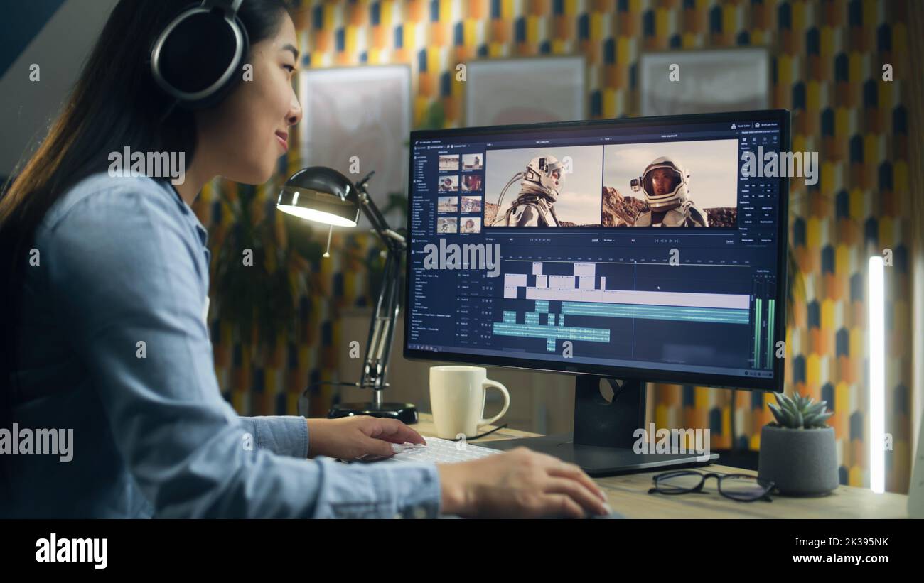 Donna asiatica nella modifica di cuffie video con astronauti per il cliente in programma sul personal computer mentre lavora al tavolo da casa ufficio. Freelance Foto Stock