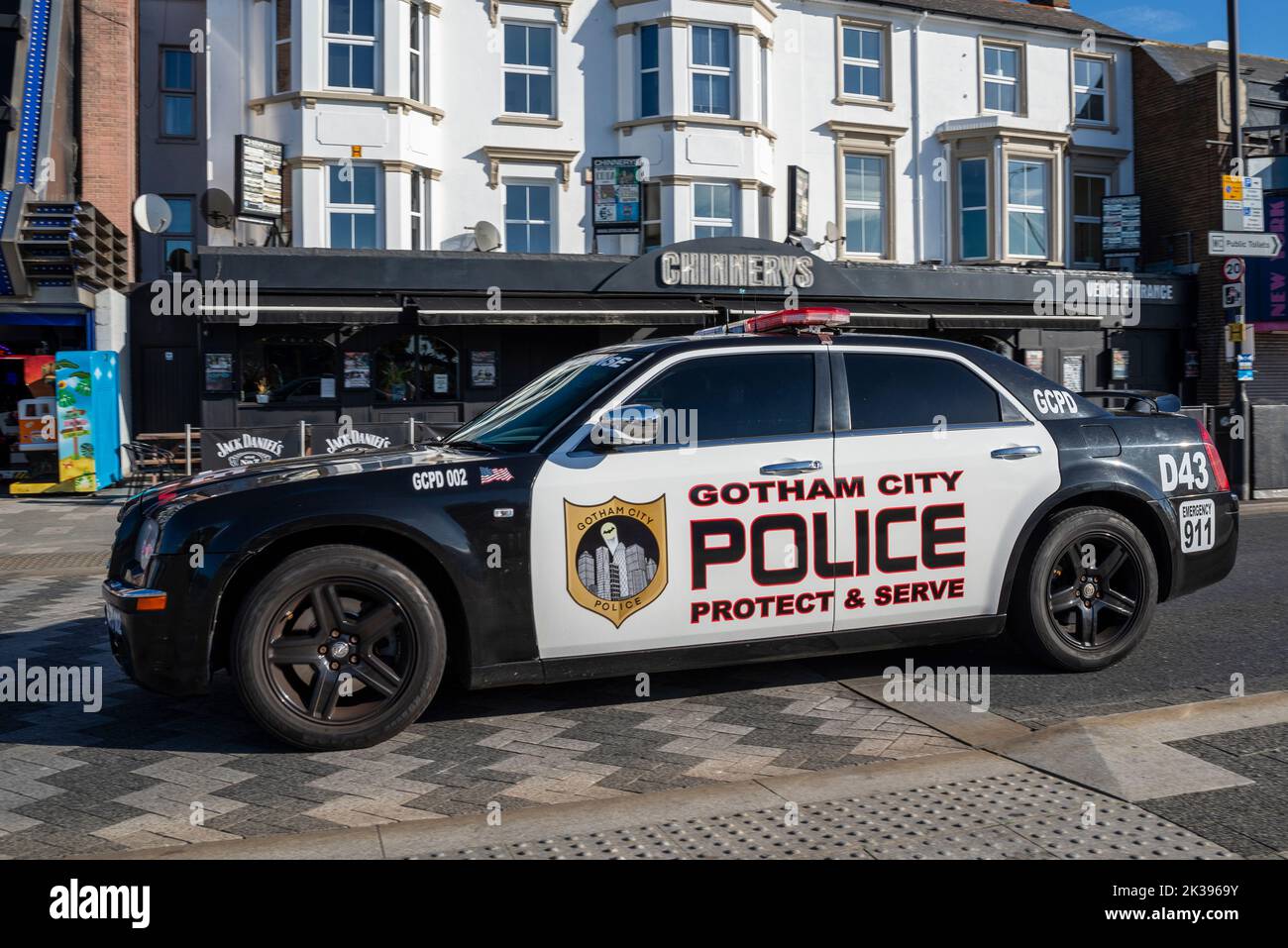 Auto della polizia di Gotham City segnata Chrysler 300 che guida sulla Marine Parade a Southend on Sea, Essex, Regno Unito. Badge, e proteggere e servire slogan Foto Stock