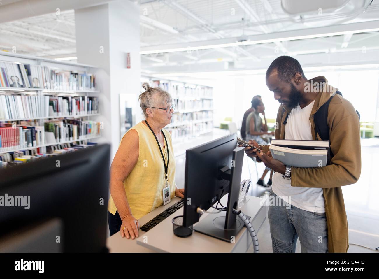 Bibliotecario aiutare studente universitario con libri in biblioteca Foto Stock