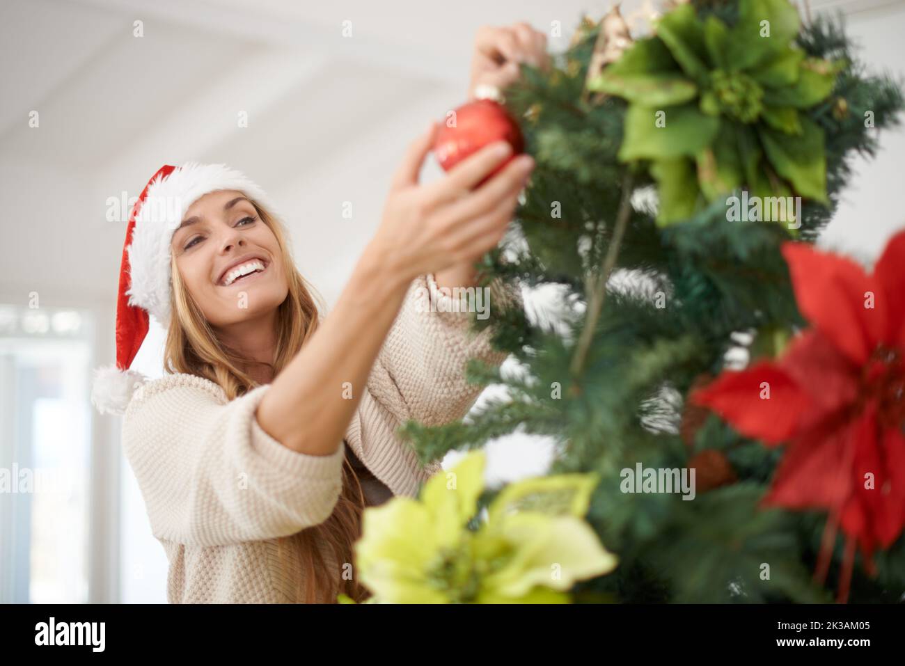 Decorare l'albero è sempre divertente. Una donna attraente decorando il suo albero di natale mentre a casa. Foto Stock