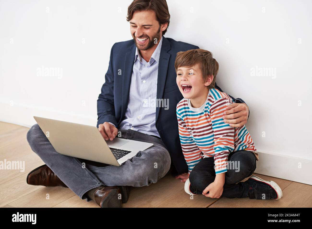 Amano passare il tempo in piedi. Un padre e un figlio seduti sul pavimento con un computer portatile. Foto Stock