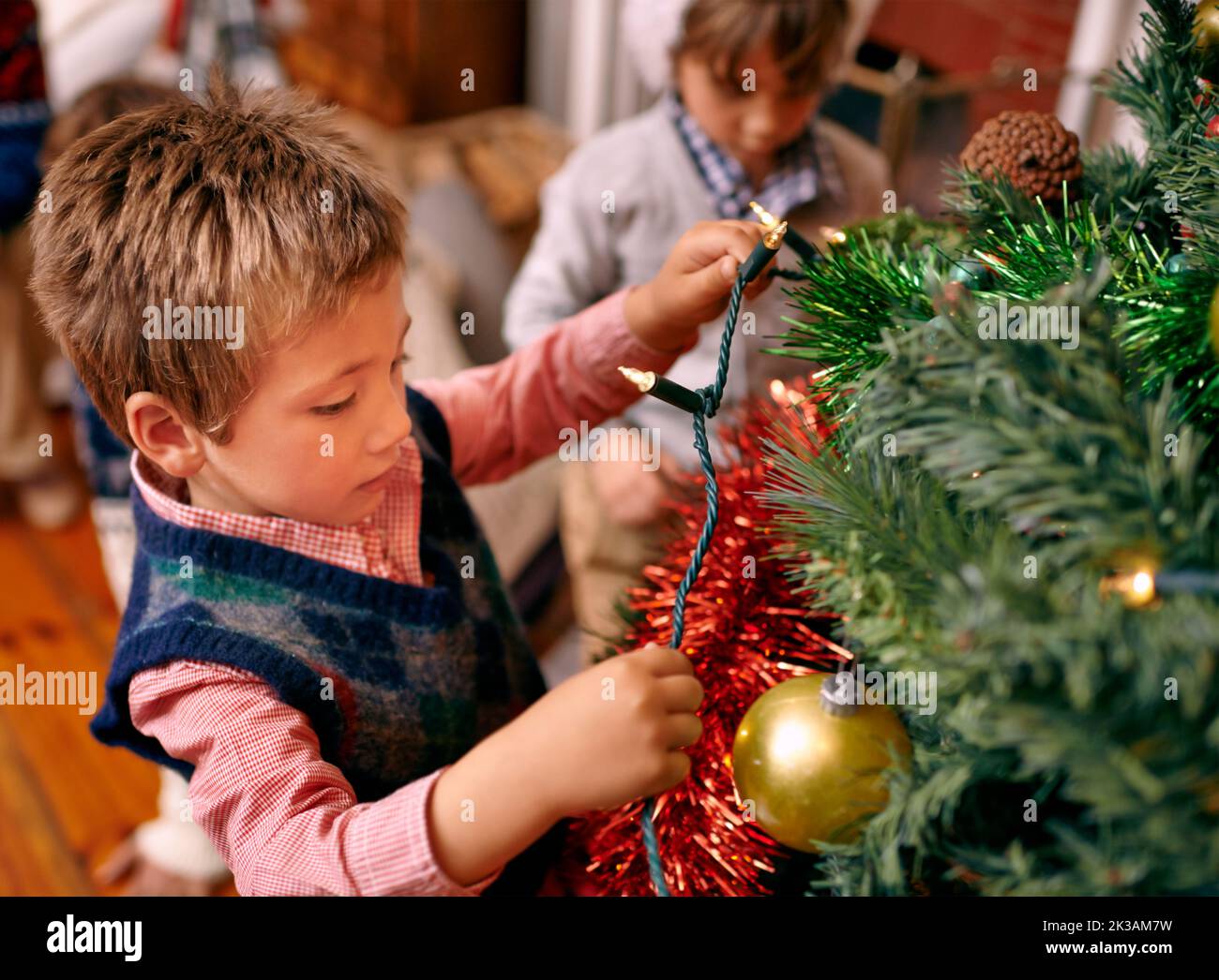 Natale è un periodo di meraviglia bambino-come... Un ragazzo giovane che decora un albero di Natale. Foto Stock