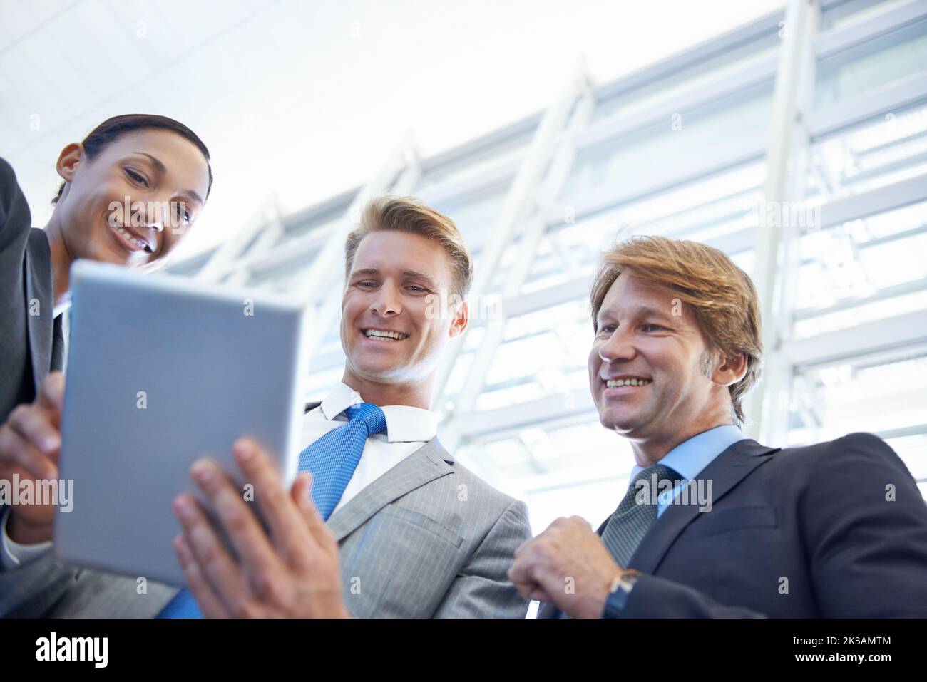 Le nostre quote sono in aumento. Un giovane uomo d'affari che mostra qualcosa ai suoi colleghi su un tablet. Foto Stock