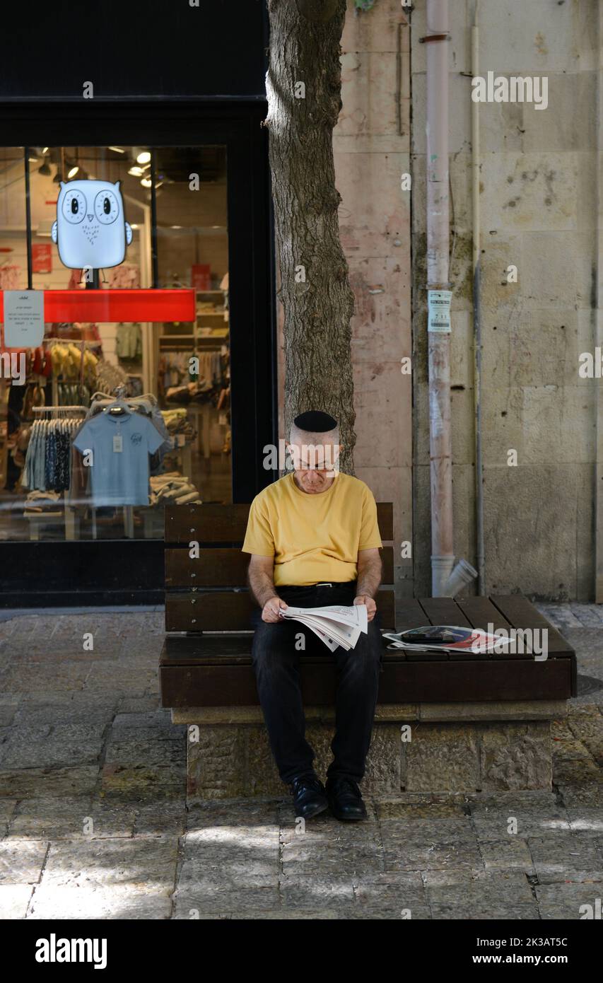 Un uomo israeliano che legge il giornale del mattino nel centro di Gerusalemme, Israele. Foto Stock