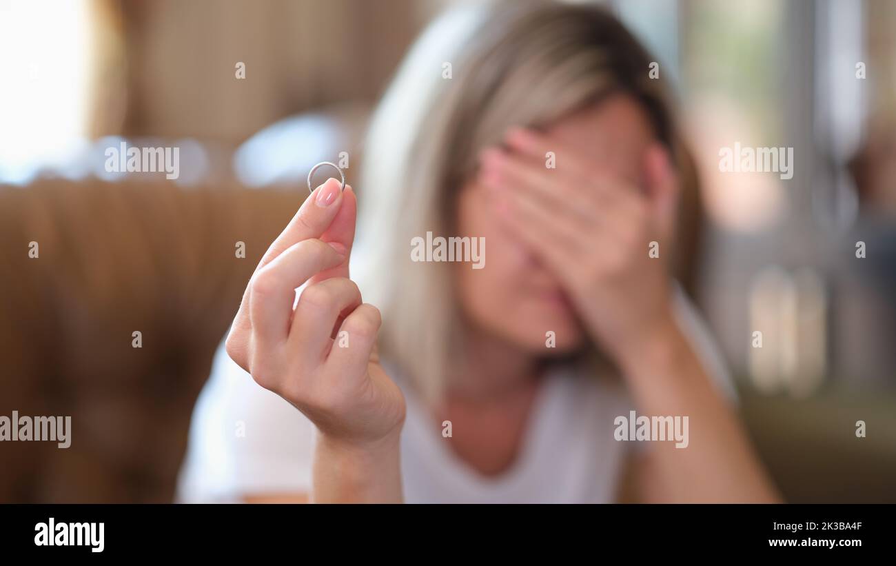 Donna sconvolto che tiene anello di fidanzamento e pensare alla dissoluzione del matrimonio o divorzio Foto Stock