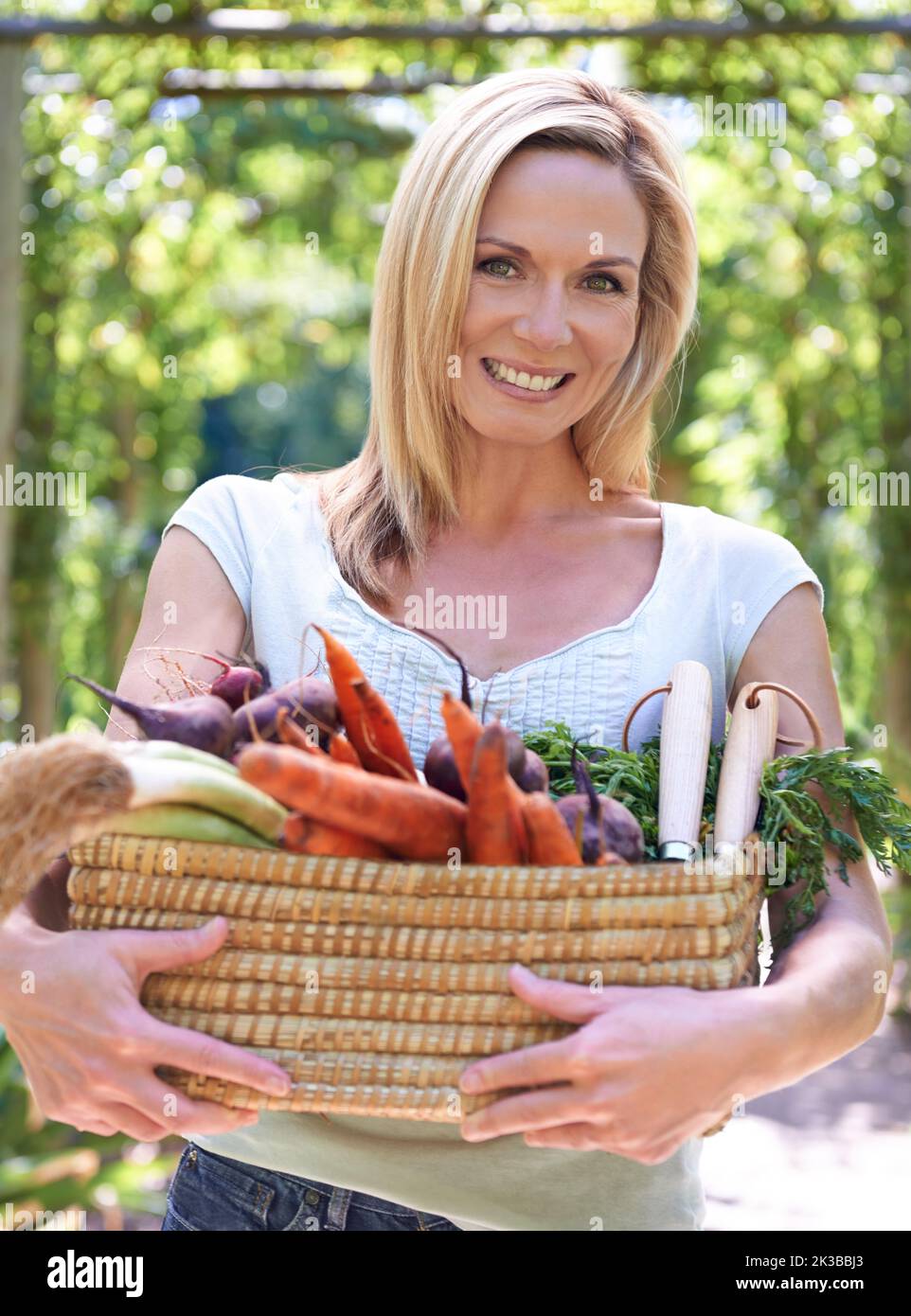 Raccogliendo le ricompense di giardinaggio devoto. Una donna che tiene un cesto di verdure appena raccolte. Foto Stock Raccogliendo le ricompense di giardinaggio devoto. Una donna che tiene un cesto di verdure appena raccolte. Foto Stock
