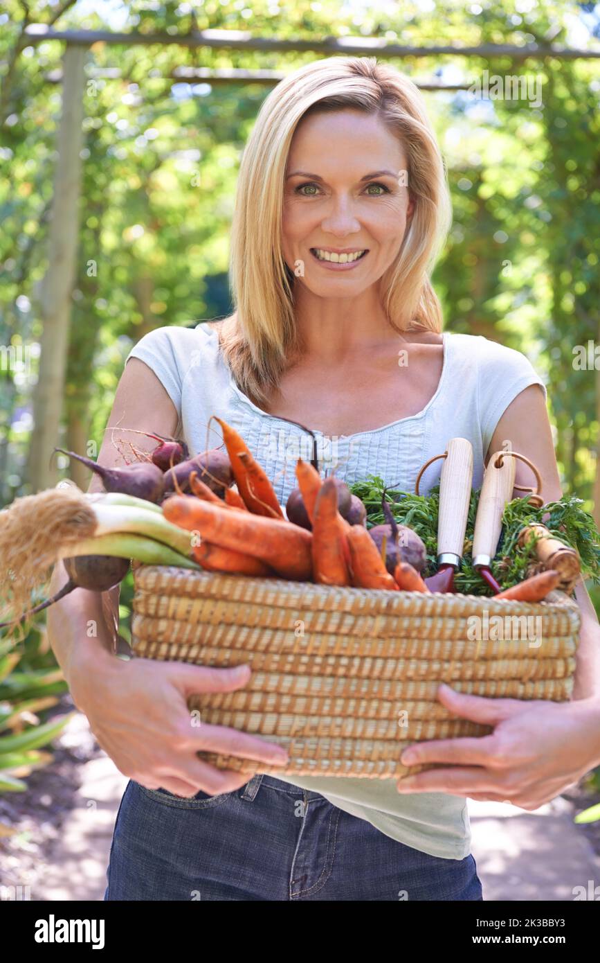 Il suo segreto per una vita sana. Una donna che tiene un cestino di verdure fresche. Foto Stock
