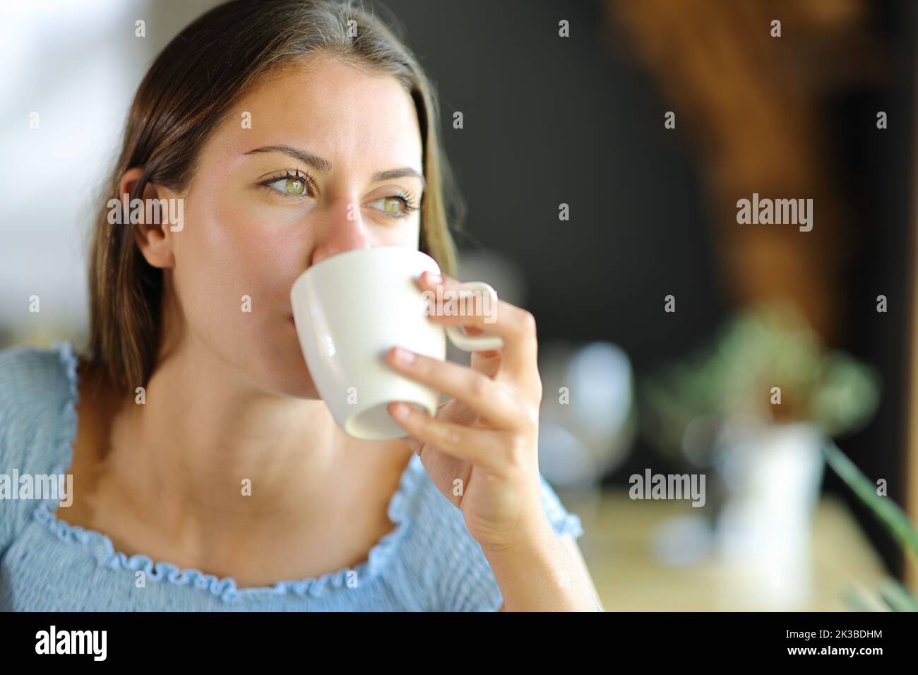 Donna felice distratta bere caffè a casa Foto Stock