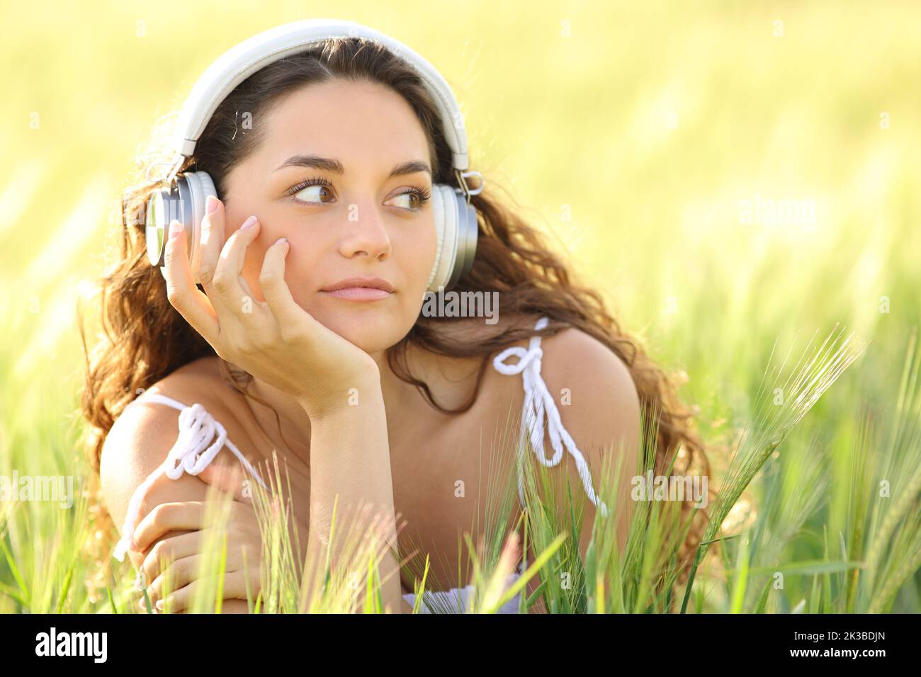 Donna rilassata che riposa ascoltando musica con le cuffie in un campo di grano Foto Stock