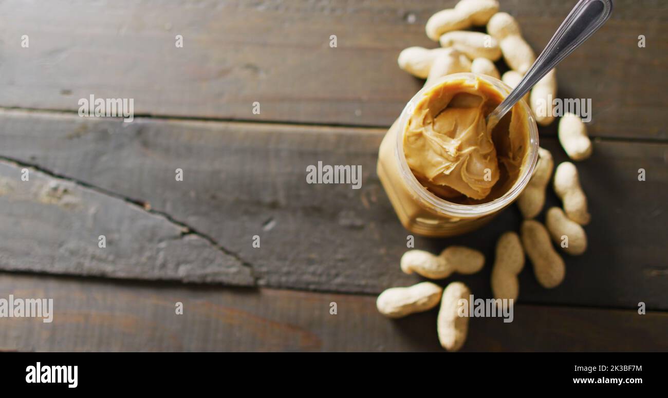 Immagine di primo piano di burro di arachidi e arachidi su sfondo di legno Foto Stock