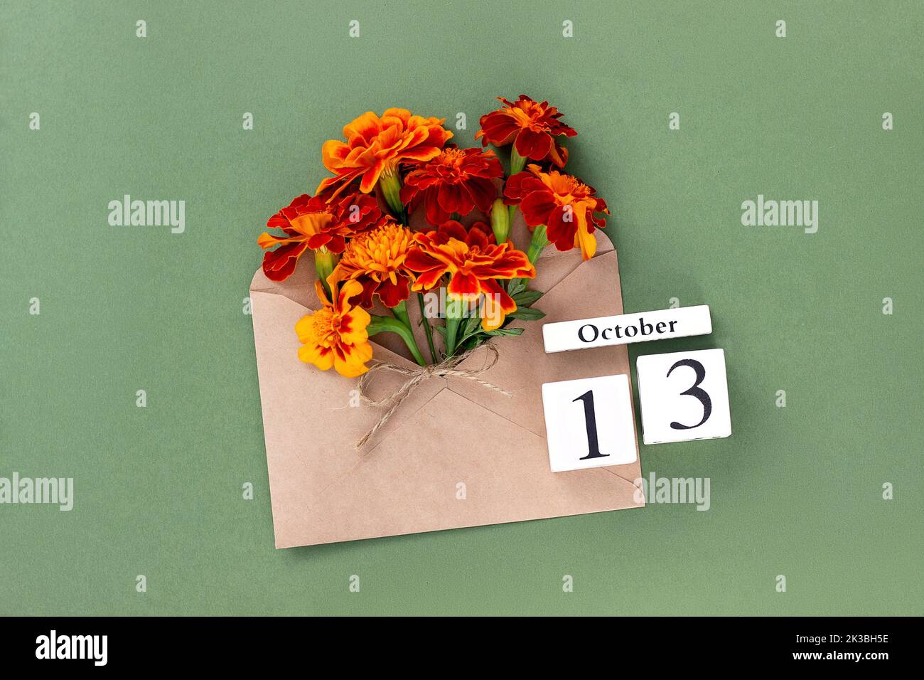 Ottobre 13. Bouquet di fiori d'arancio in busta artigianale e data di calendario su sfondo verde. Concetto minimo Ciao autunno. Modello per il progetto, gr Foto Stock