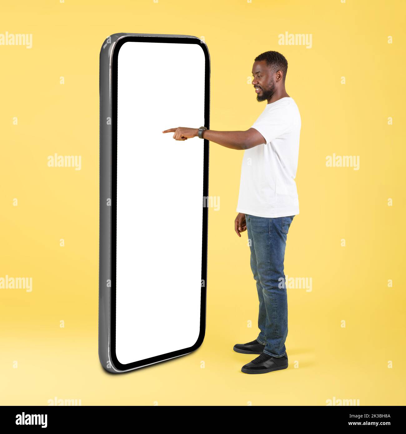 Un ragazzo africano che usa un grande telefono che tocca lo schermo vuoto in studio Foto Stock